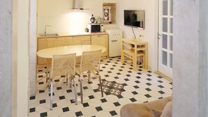 En kompakt bolig med tekøkken, spiseplads og et fjernsyn.