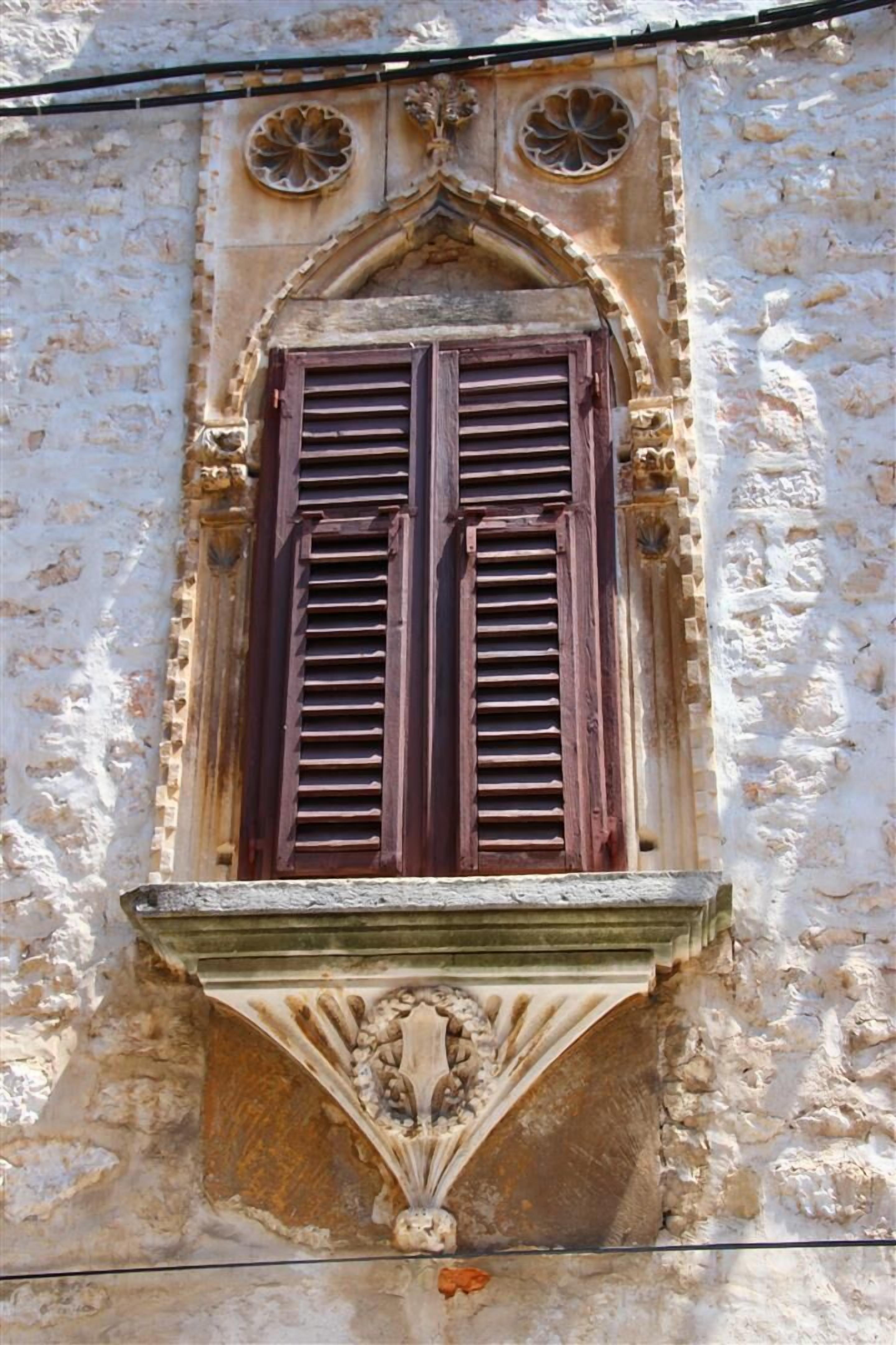 A window with wooden shutters and a decorative stone frame.