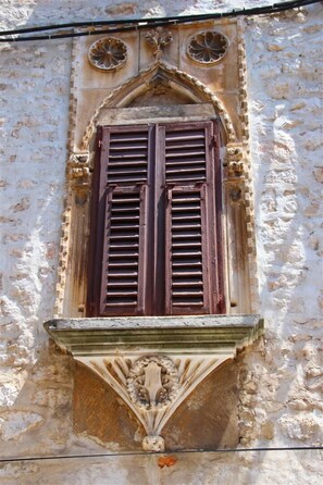 A window with wooden shutters and a decorative stone frame. - Central Apartments - Integrated Hotel Zadar (Zadar)