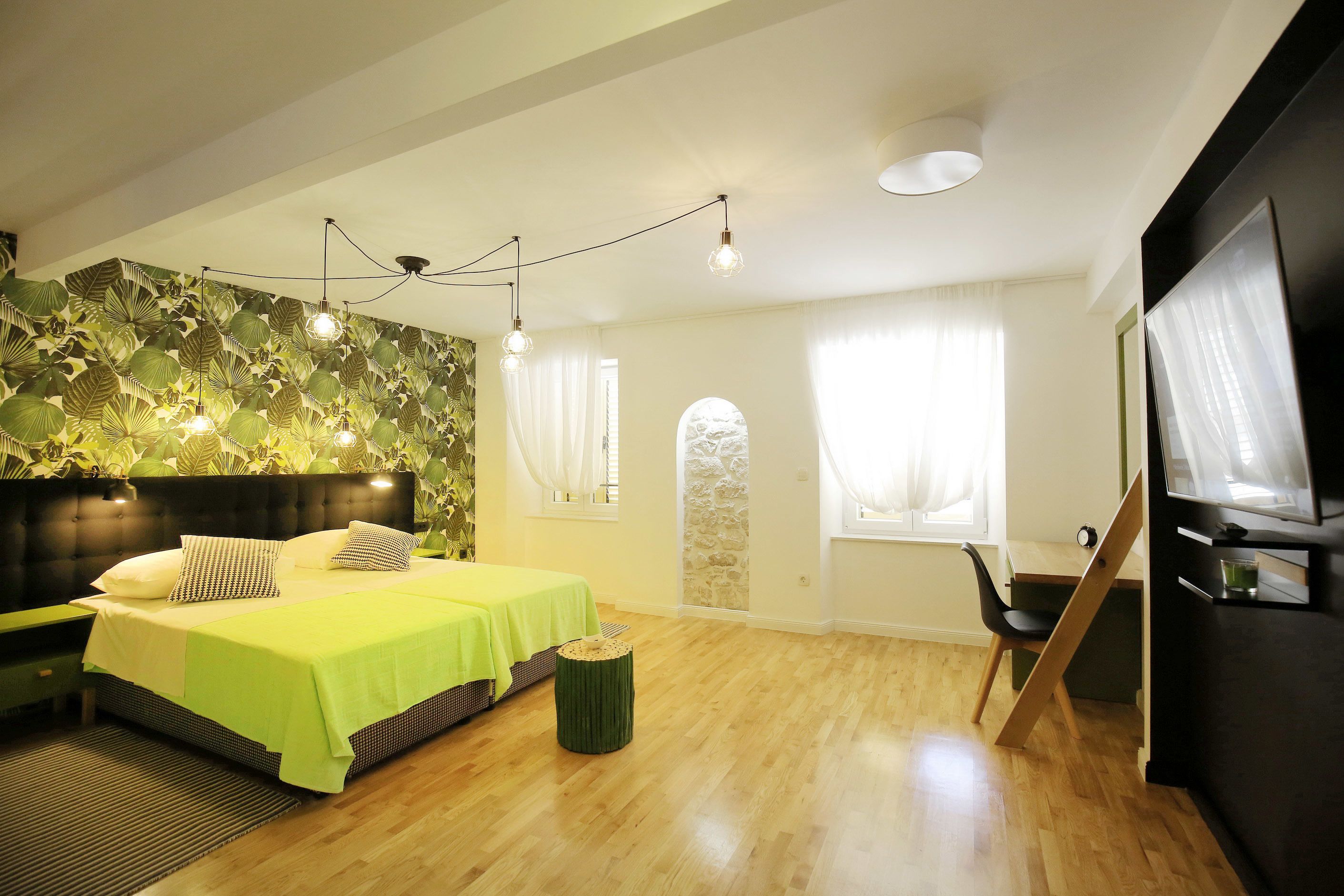 A modern bedroom with a bed, bedside tables, a desk, and a television.
