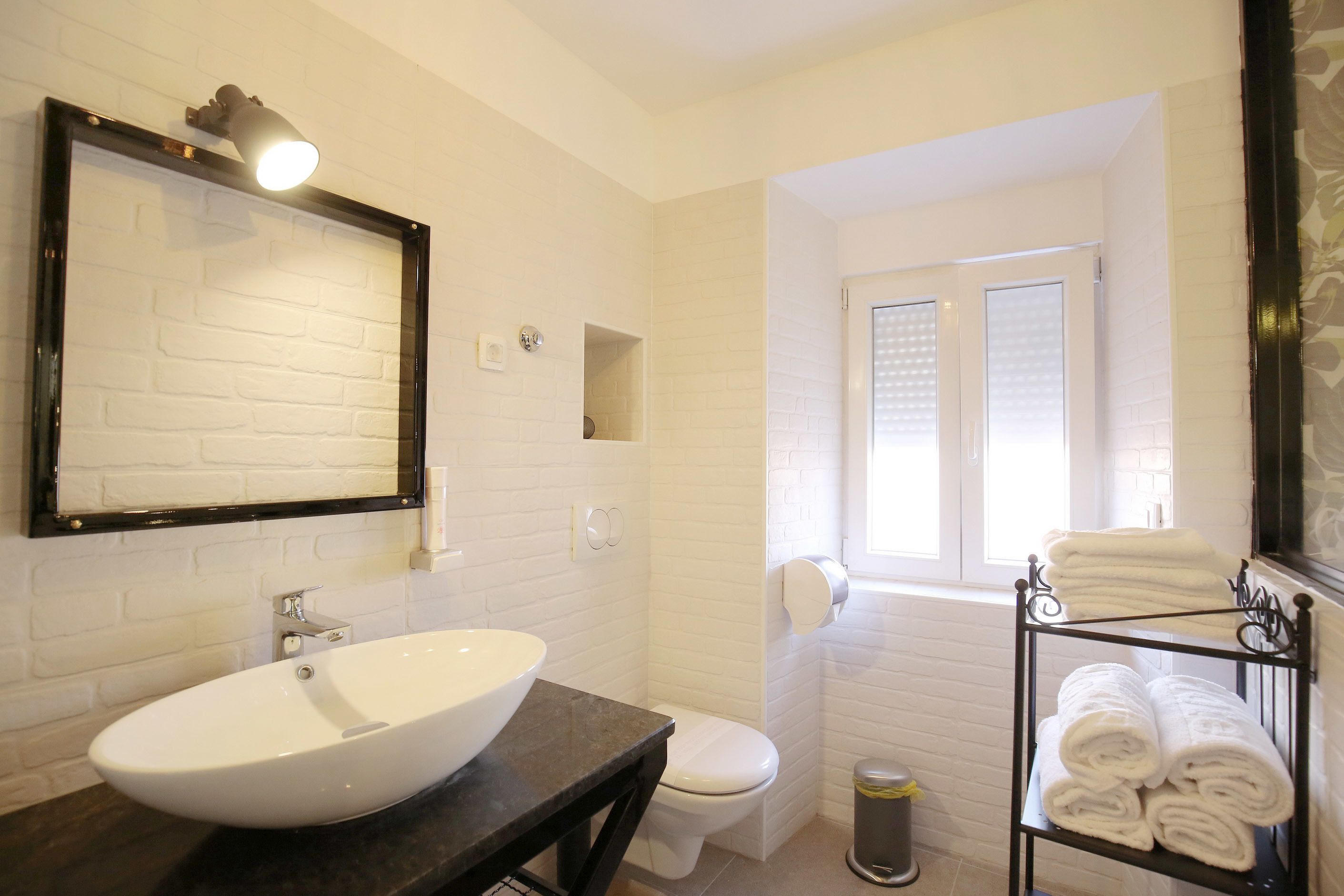 A bathroom with a white sink, a toilet, a mirror, and a towel rack.