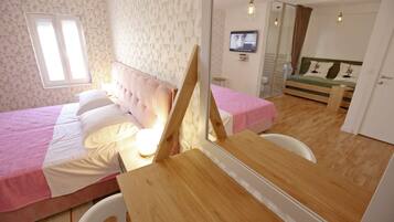 A bedroom with a bed, a mirror, a TV, and a wooden table.