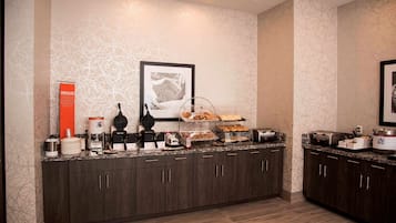 A modern kitchen with dark wood cabinets, a granite countertop, and various appliances including a coffee maker, toaster, and food display.