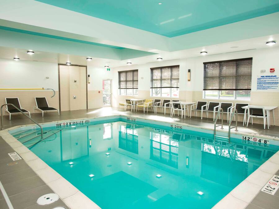 An indoor swimming pool with clear lane markings, a shallow end, and a diving board.