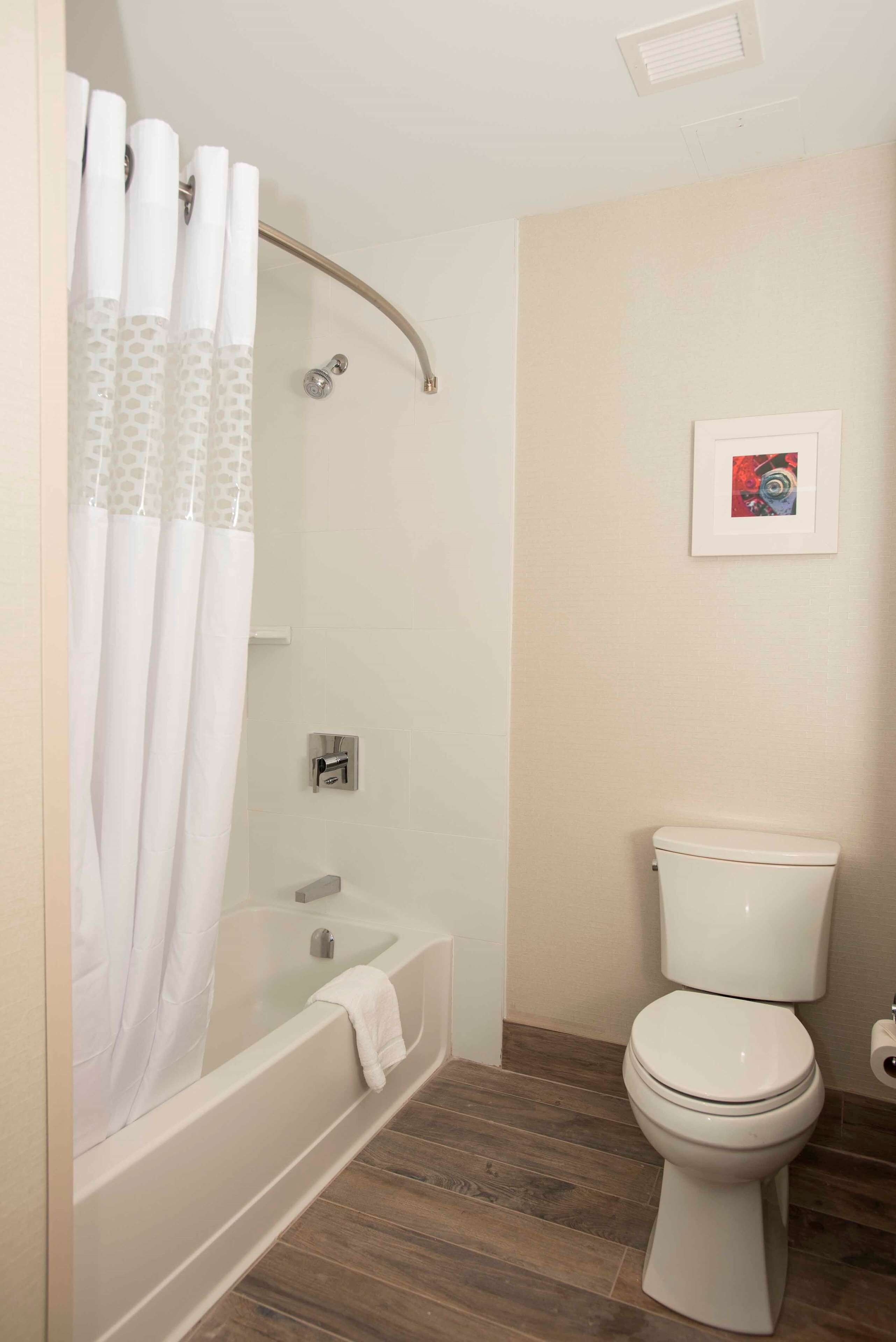 A bathroom with a bathtub, toilet, and shower curtain.
