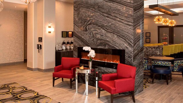 Un vestíbulo moderno con chimenea de mármol, asientos rojos e iluminación decorativa.