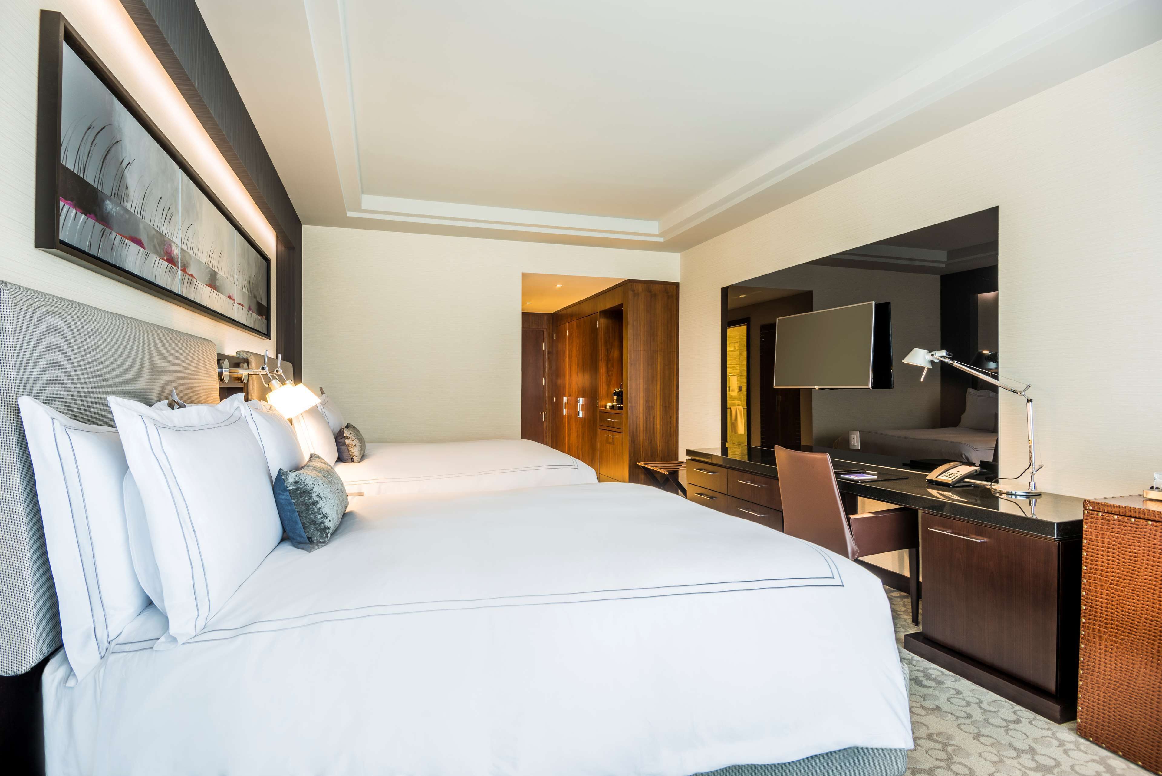 Habitación de hotel con una cama grande, un escritorio, una silla, un televisor de pantalla plana y un cuadro en la pared.