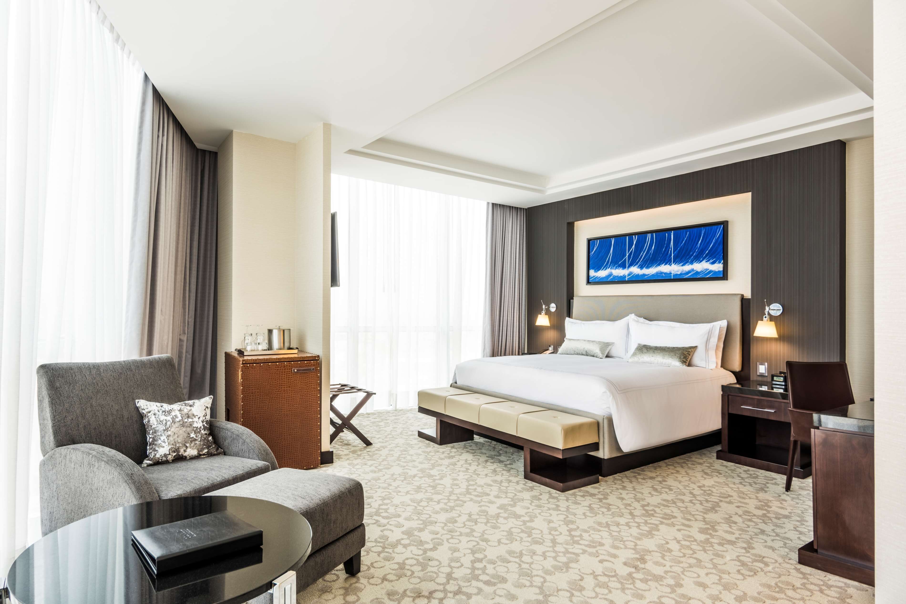 A hotel room with a large bed, a sofa, a small table, and a desk.