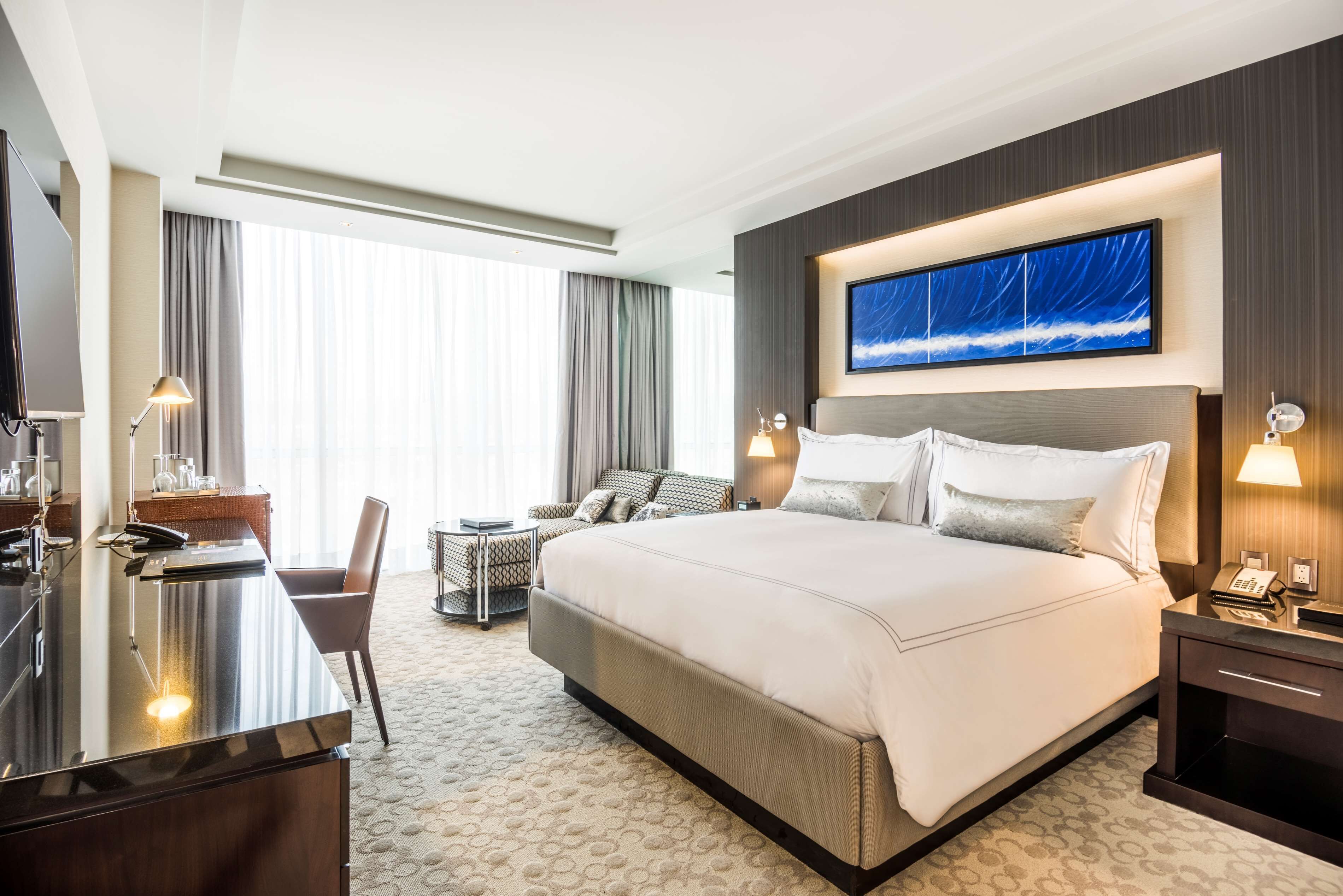 Une chambre d’hôtel moderne, dotée d’un grand lit, d’un bureau et d’une télévision.