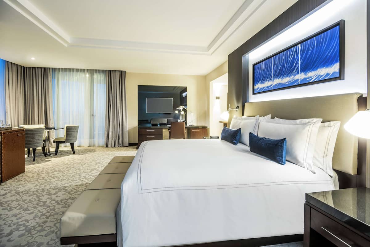 A hotel room with a large bed, a desk, and a chair.