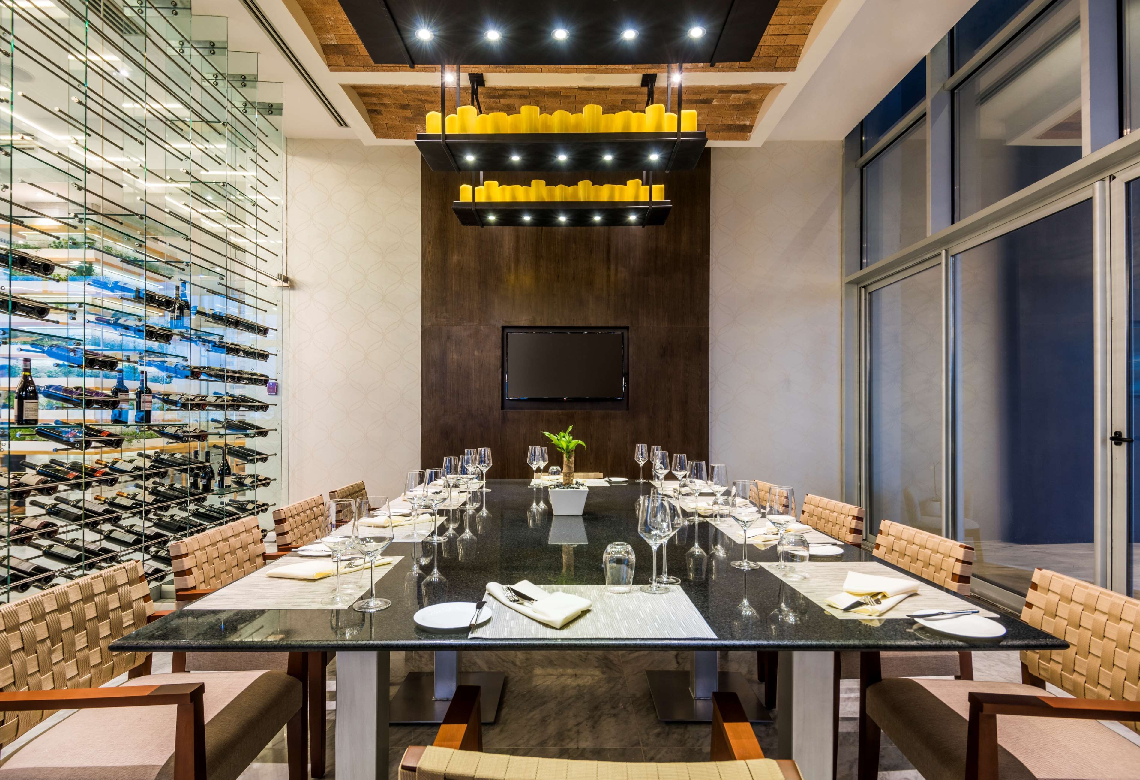 Un salón de conferencias con una mesa de vidrio, sillas y una estantería para vinos.