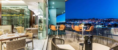 A restaurant with a city view, modern furniture, and a glass wall.