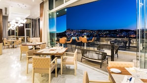 A modern restaurant with a terrace overlooking a cityscape at night. - Hyatt Regency San Luis Potosi (San Luis Potosi)