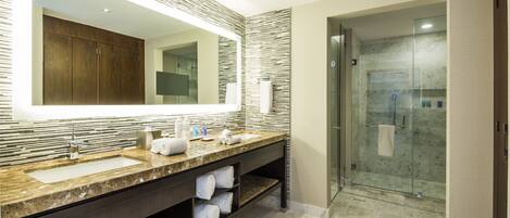 A modern bathroom with a large mirror, dual sinks, a shower, and a marble countertop.