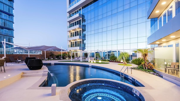 A modern hotel with a swimming pool, outdoor seating, and a view of the cityscape. - Hyatt Regency San Luis Potosi (San Luis Potosi)