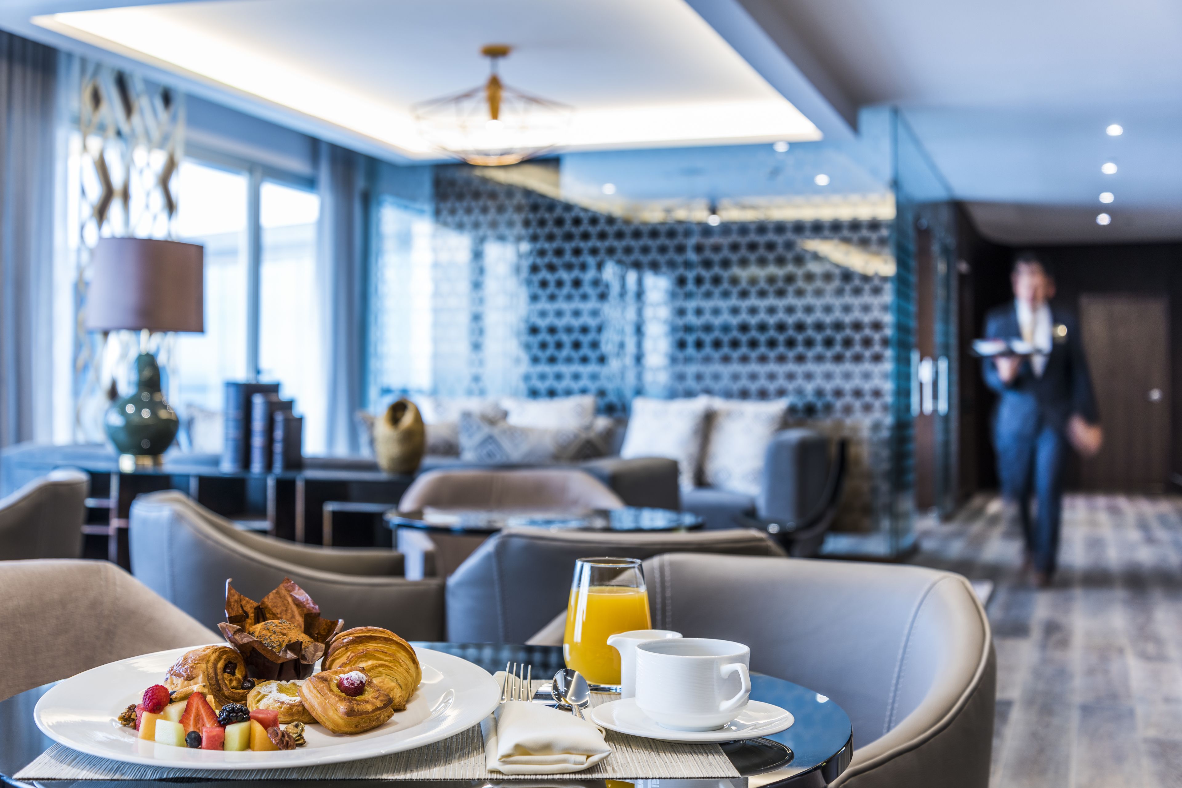A breakfast setting with croissants, fruits, and orange juice on a table.
