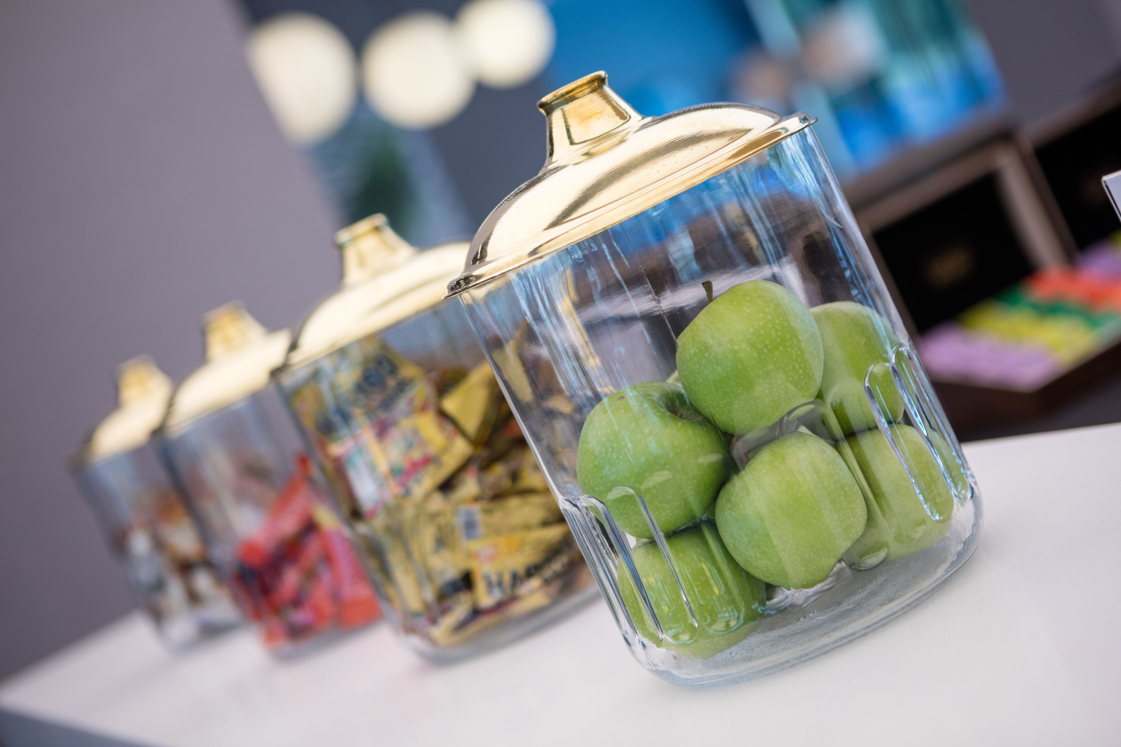 Des bocaux en verre avec des couvercles, contenant des pommes vertes et d’autres en-cas.