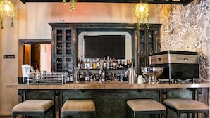A bar area with a stone wall, hanging lights, and bar stools. - Casona de los Sapos Hotel Boutique (Puebla)
