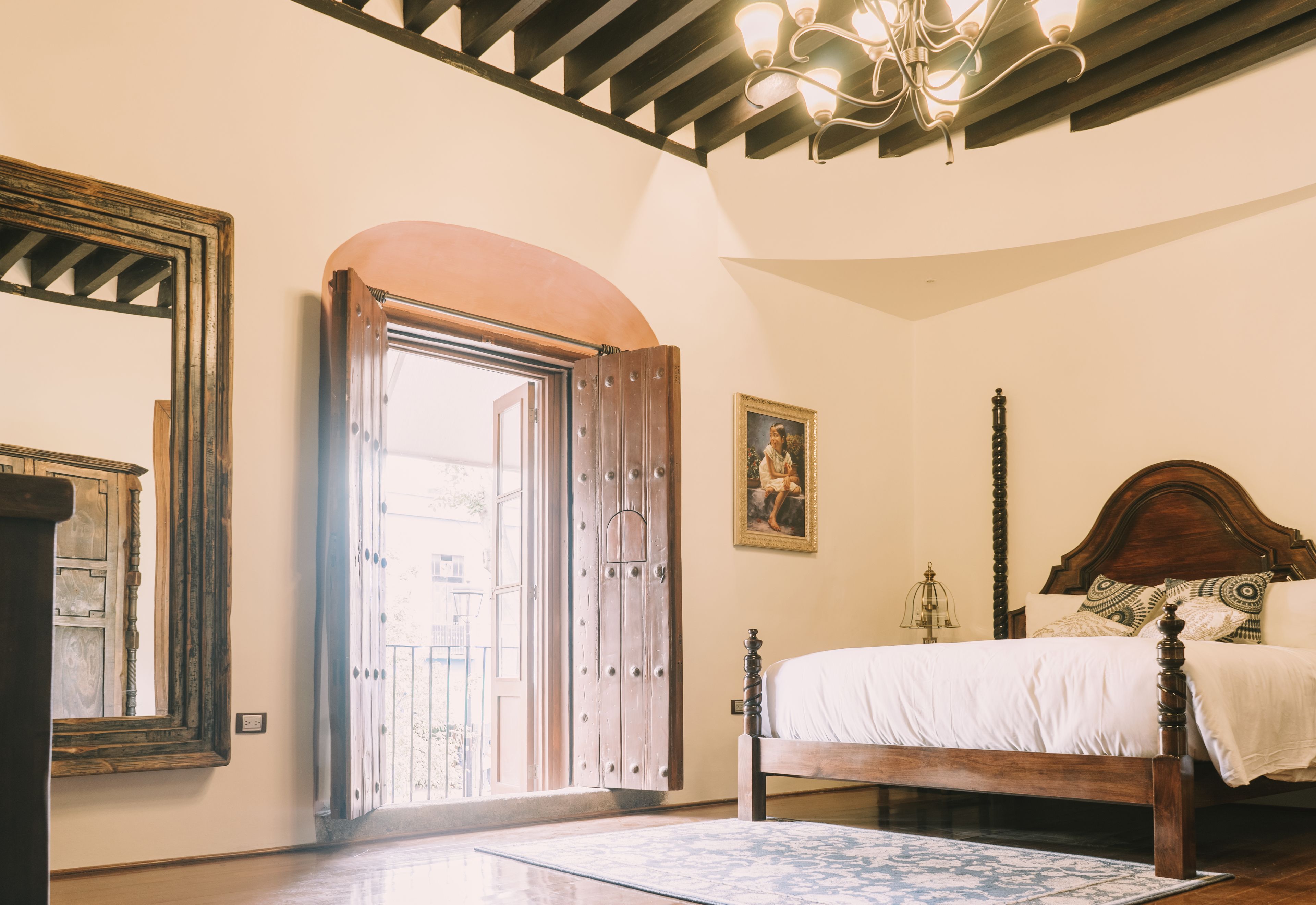 Un dormitorio con cama de madera, un amplio arco y una araña.