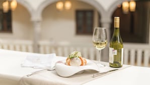 A dining table with a white tablecloth, a bottle of white wine, and a glass of wine. - Casona de los Sapos Hotel Boutique (Puebla)