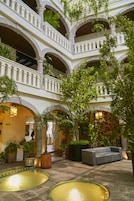 Un patio de varios niveles con arcos, macetas con plantas y una zona de estar.