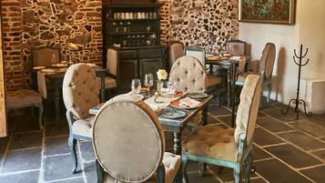 A dining area with a stone wall, wooden ceiling, and hanging light fixtures.
