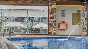 A swimming pool with a wooden deck, stone walls, and a lifebuoy on the wall. - Casona de los Sapos Hotel Boutique (Puebla)