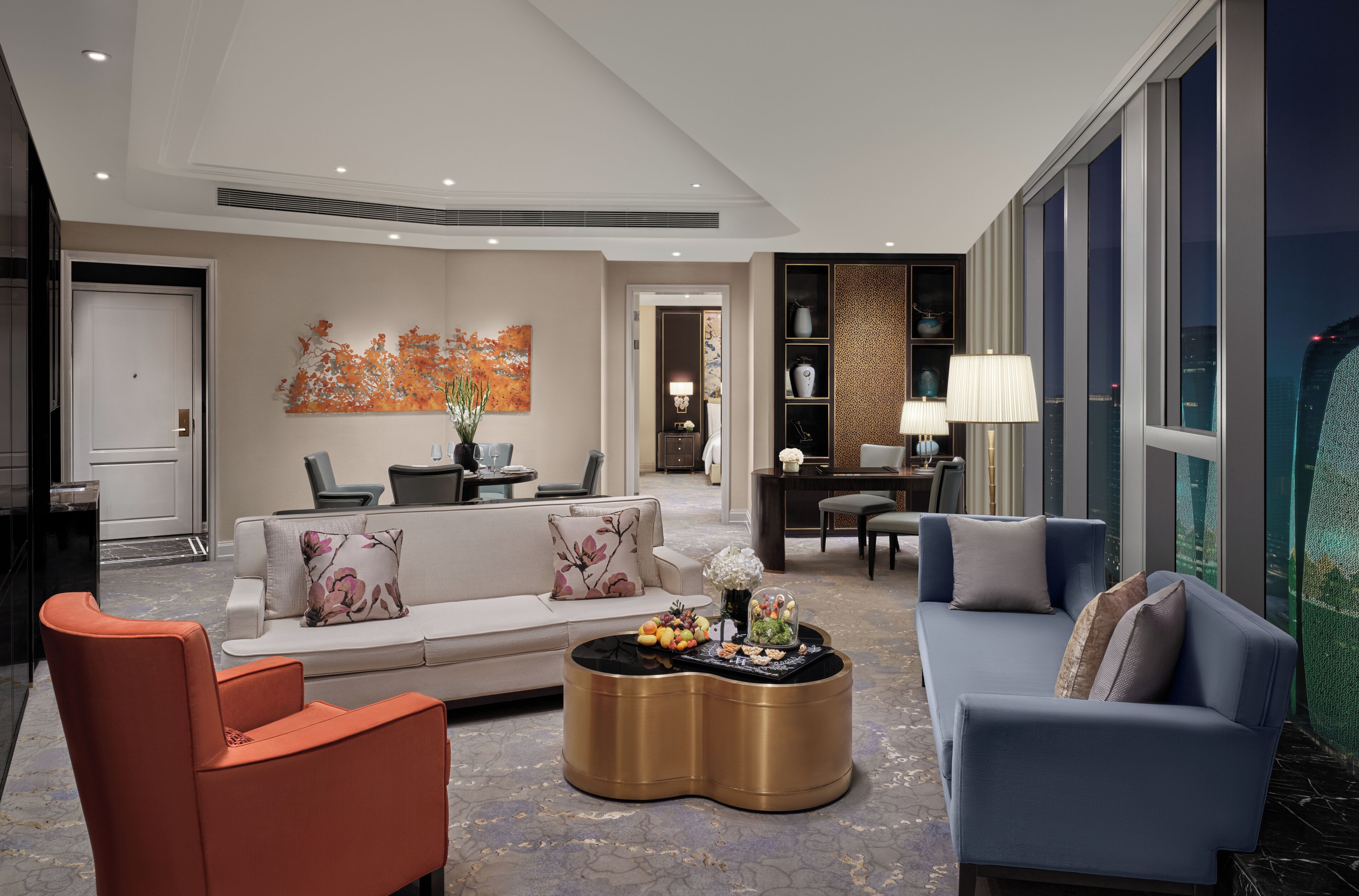 A modern living room with a sofa, armchairs, a coffee table, and a dining area with a lamp.