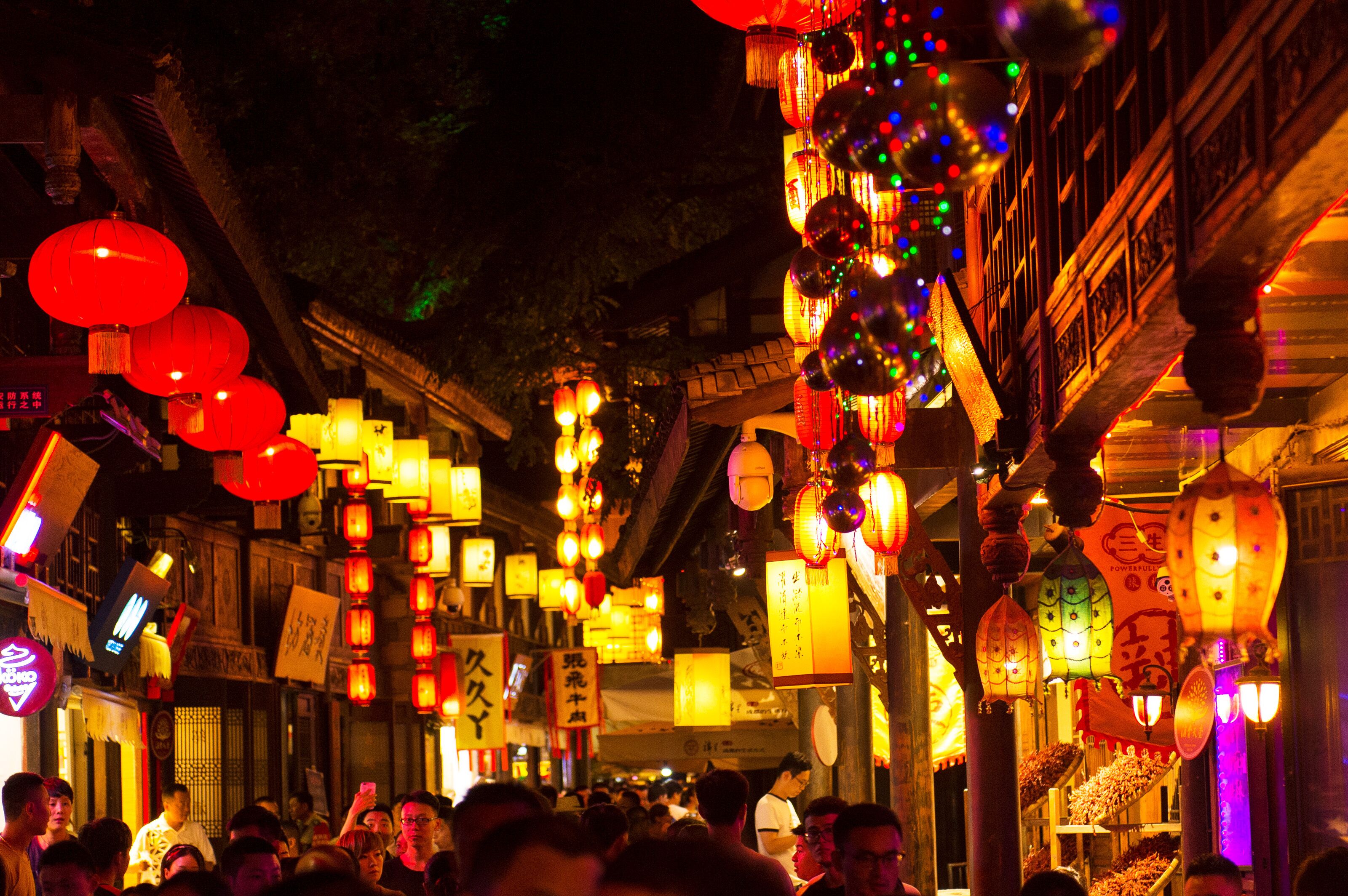 A crowded street with traditional architecture and hanging lanterns.