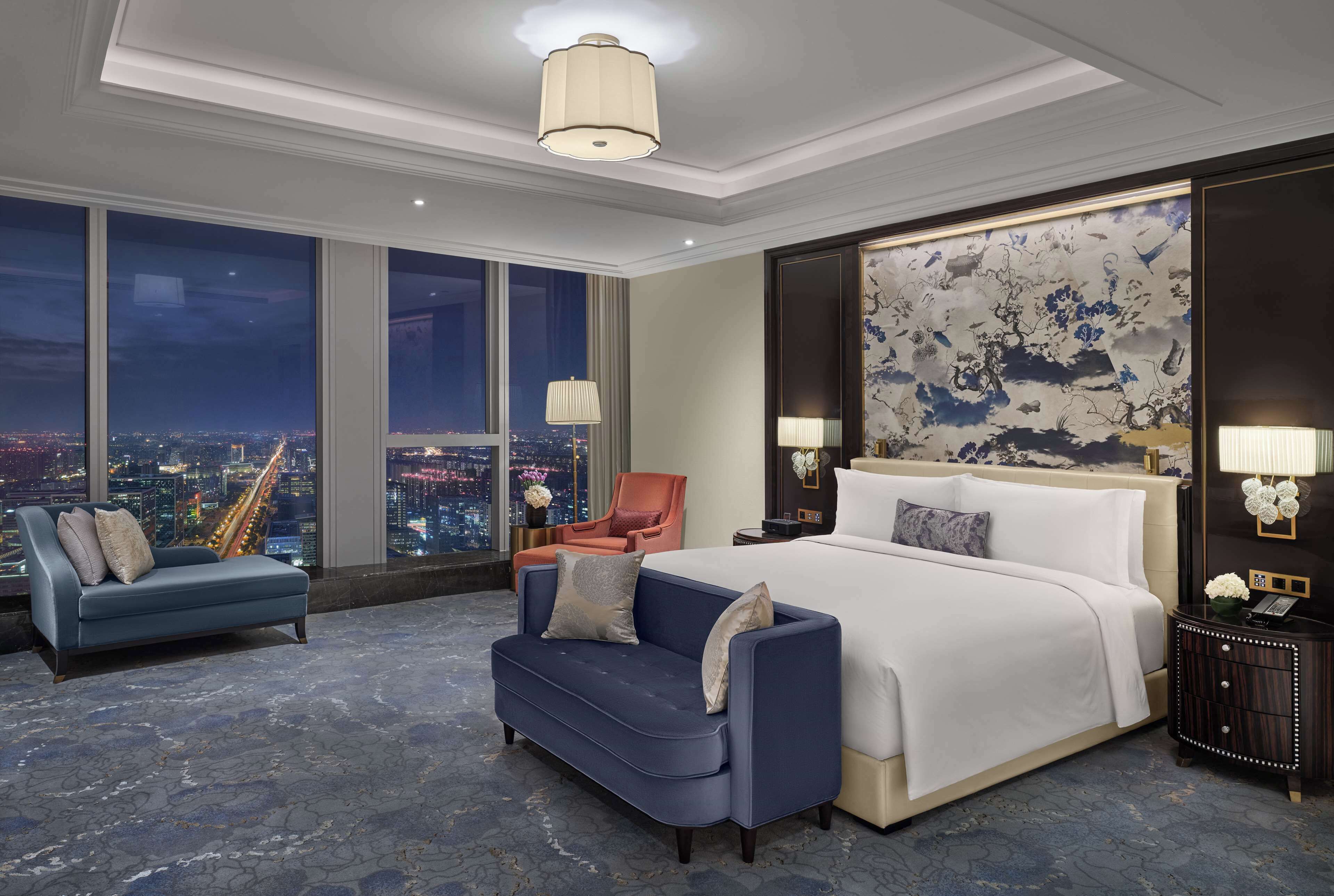 A modern hotel room with a large bed, a sofa, and a nightstand.