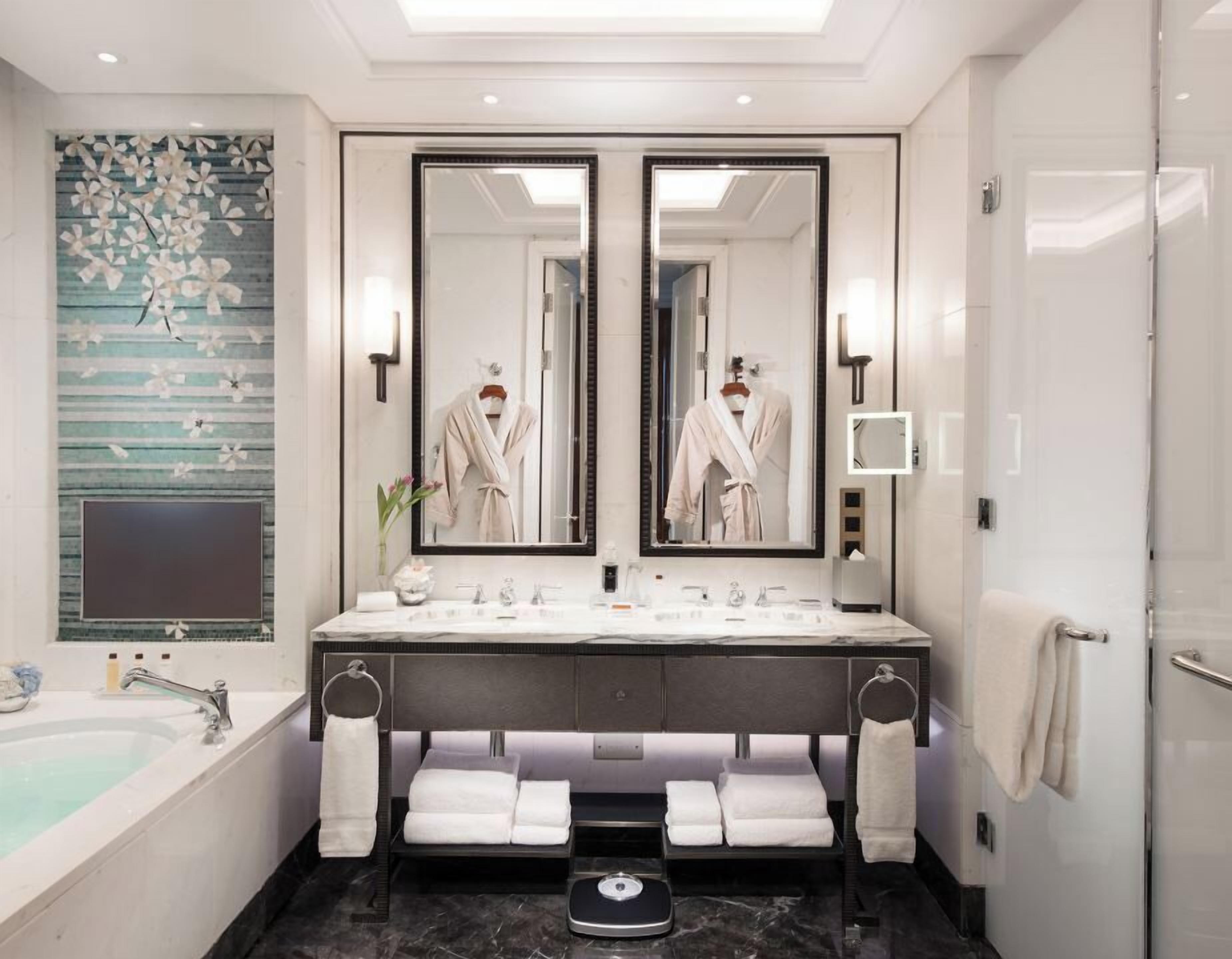 A modern bathroom with a double sink vanity, a large mirror, a bathtub, and a scale.
