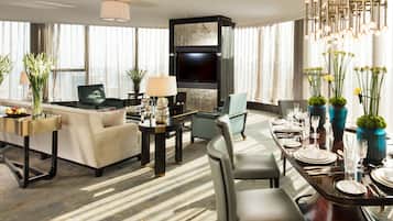 Ein modernes Hotelzimmer mit Wohnbereich, Essbereich und einem großen Fenster mit Vorhängen.