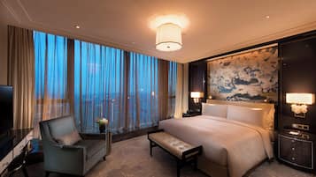 A hotel room with a large bed, a desk, a chair, and a TV.