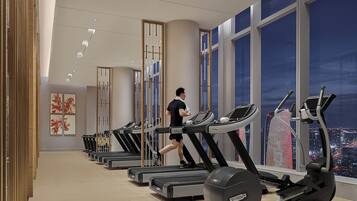 A gym with treadmills and elliptical machines, large windows with a city view, and a modern interior design.