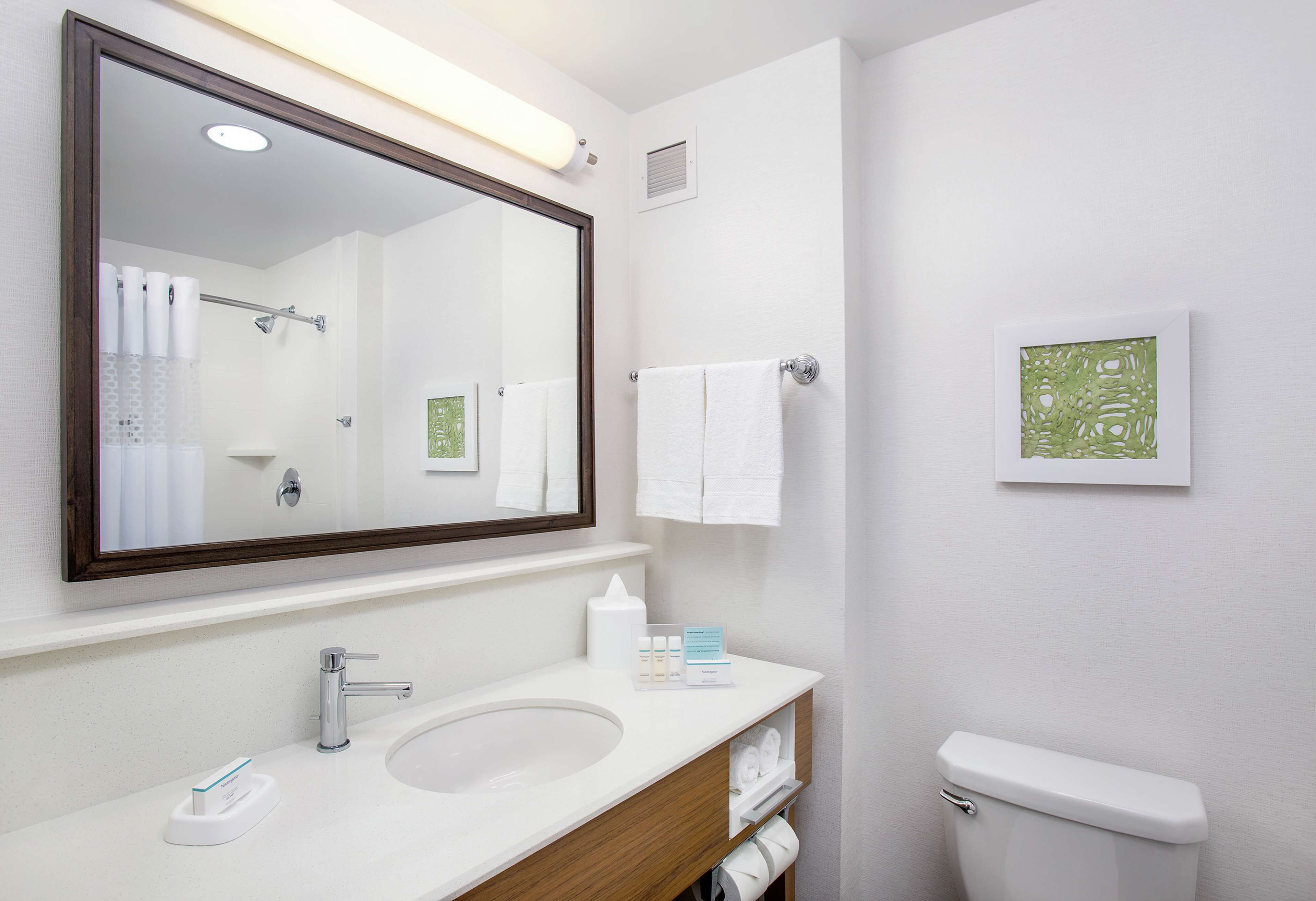 A bathroom with a large mirror, a sink, a toilet, and a towel rack.