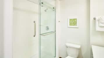 A modern bathroom with a glass-enclosed shower, a white toilet, and a framed artwork on the wall.