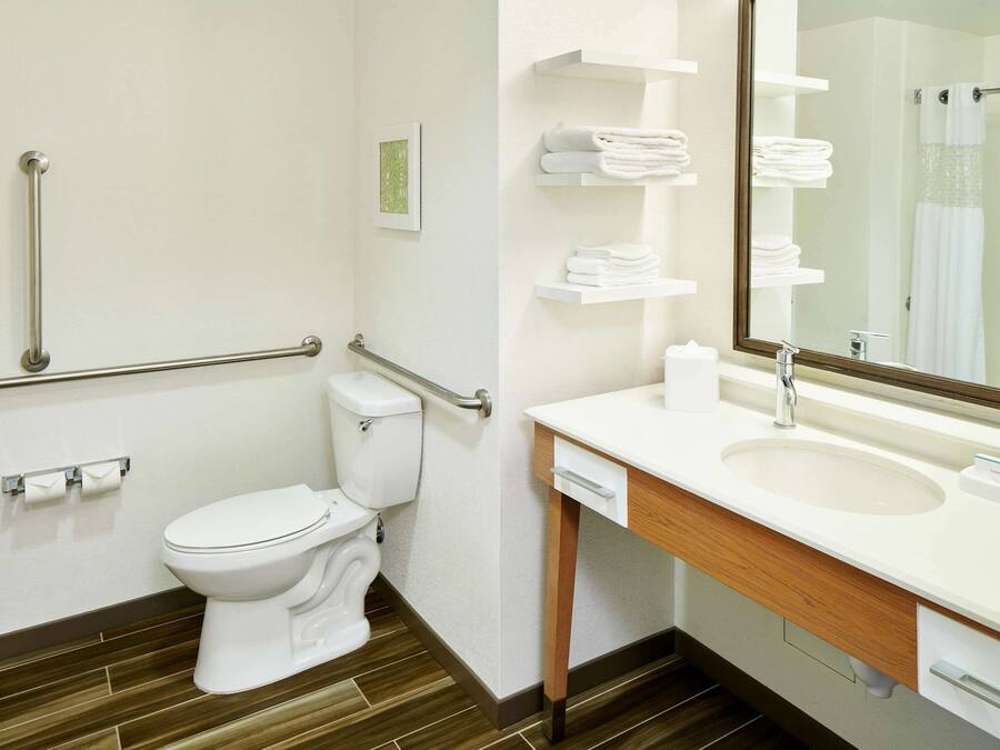 A bathroom with a toilet, a sink, a mirror, and a shower area.