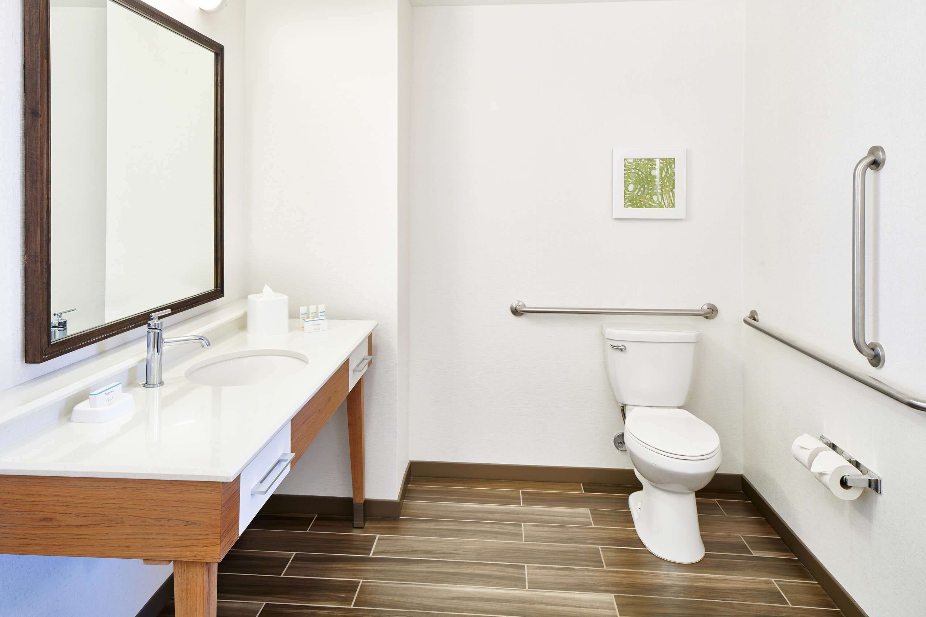 A modern bathroom with a white sink, mirror, and toilet.
