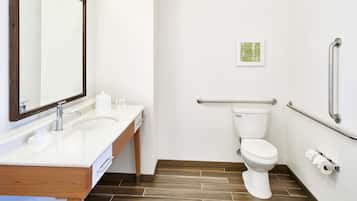 Un baño moderno con lavamanos, espejo y retrete blancos.