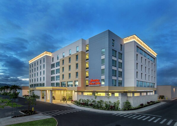 A modern hotel with a flat facade, multiple floors, and a prominent 'Hampton Inn & Suites' sign.