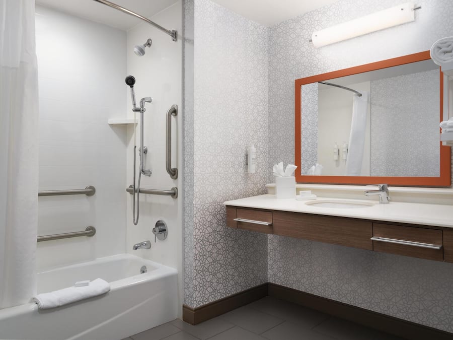 Een moderne badkamer met douche, bad, wastafel en een grote spiegel.