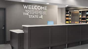 En modern hotellreception med en skylt som lyder ”Välkommen till Empire State”, en minibar och ett ”Hilton Honors”-märke.