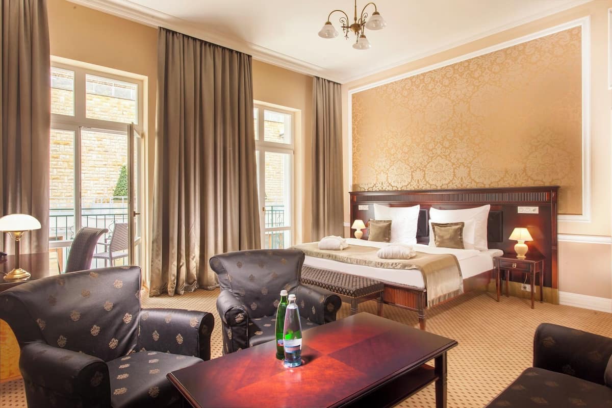 A hotel room with a large bed, two bedside tables, a desk, and a chair.