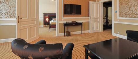 A hotel room with a large bed, a TV mounted on the wall, a dining table, and a patterned carpet.
