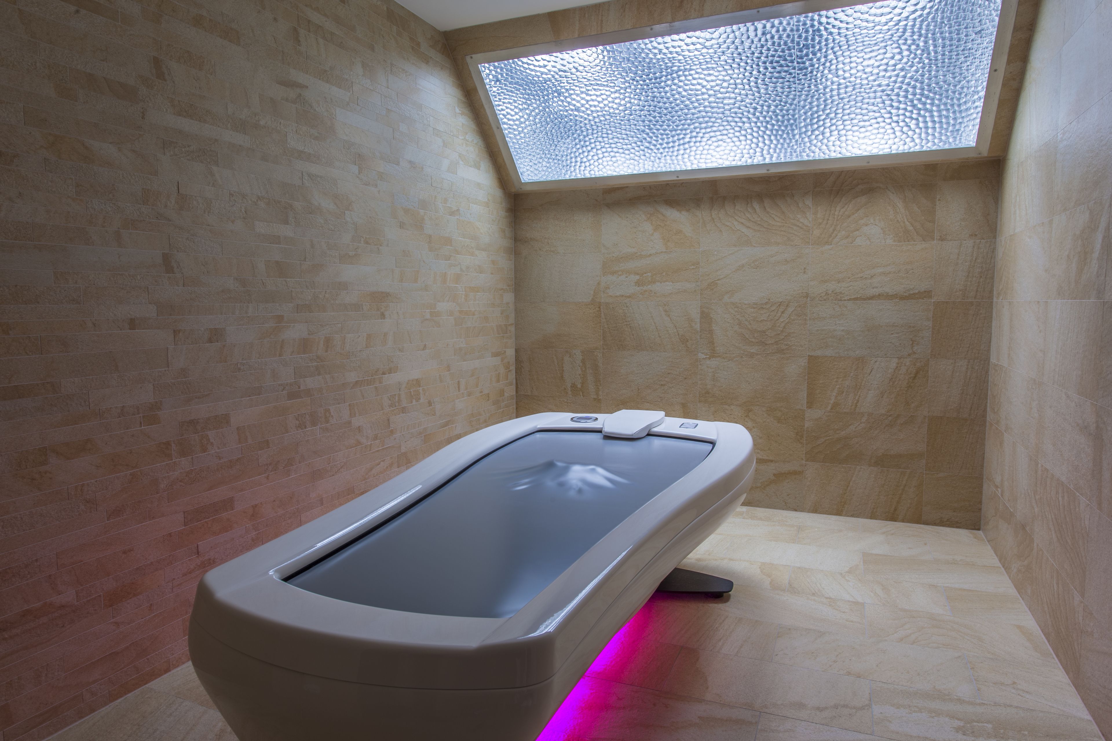 Un cuarto de spa con una bañera de hidromasaje cubierta con vidrio, paredes de madera y tragaluces.