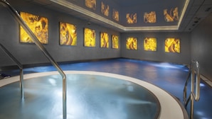 A large indoor swimming pool with a circular design, surrounded by walls with illuminated artwork. - Luxury Spa Hotel OLYMPIC PALACE (Karlovy Vary)
