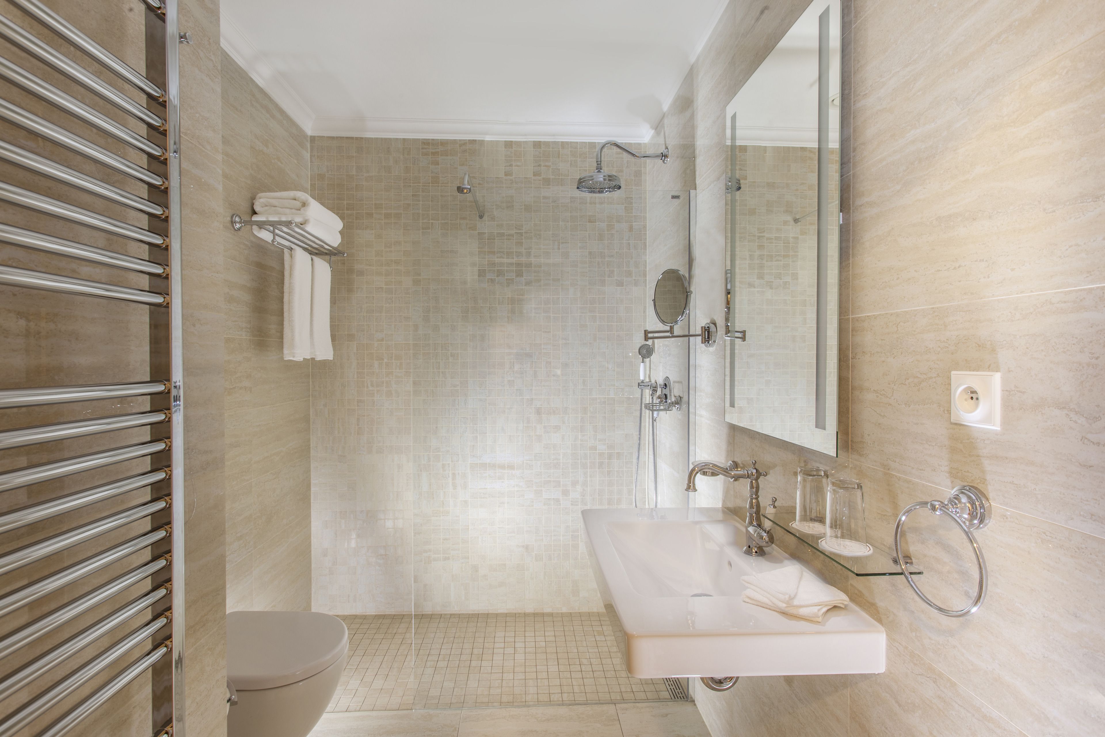 Une salle de bain moderne avec une douche à parois de verre, des toilettes, un lavabo avec un miroir et un porte-serviettes.