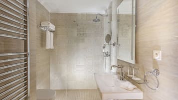 A modern bathroom with a glass shower enclosure, a toilet, a sink with a mirror, and a towel rack.