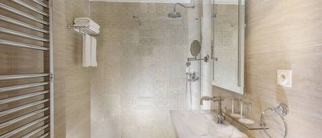 Une salle de bain moderne avec une douche à parois de verre, des toilettes, un lavabo avec un miroir et un porte-serviettes.