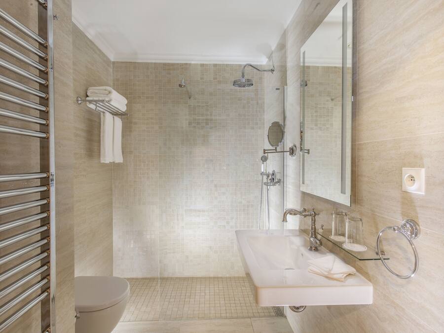 A modern bathroom with a glass shower enclosure, a toilet, a sink with a mirror, and a towel rack.